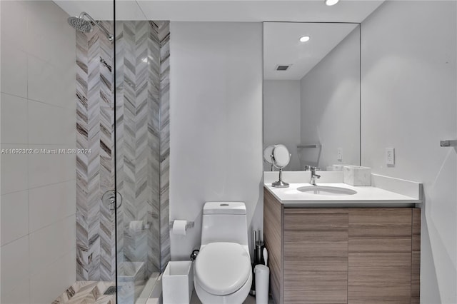 bathroom featuring toilet, vanity, and tiled shower