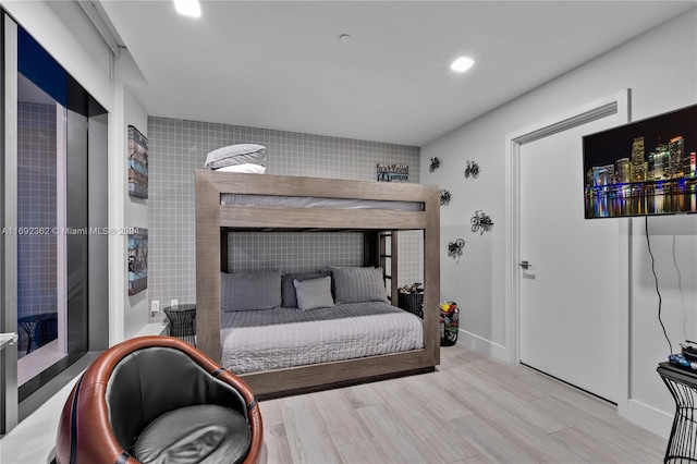 bedroom with tile walls and light hardwood / wood-style flooring