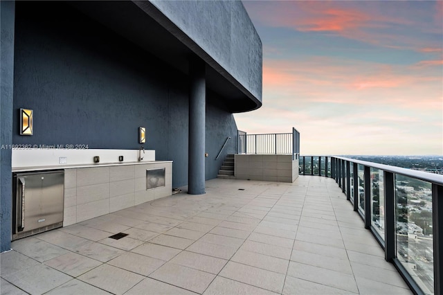 patio terrace at dusk featuring a balcony and sink