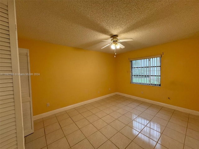 spare room featuring light tile patterned flooring, ceiling fan, and a textured ceiling