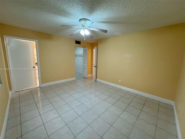 unfurnished room with a textured ceiling, light tile patterned floors, and ceiling fan