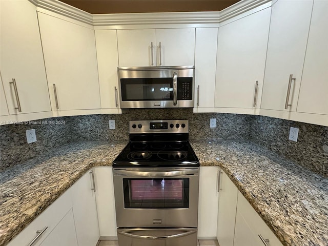 kitchen featuring dark stone countertops, white cabinetry, decorative backsplash, and appliances with stainless steel finishes