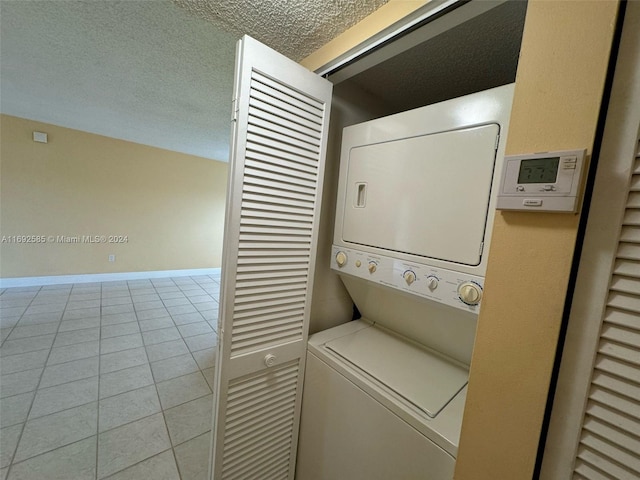 washroom featuring light tile patterned flooring, a textured ceiling, and stacked washer / drying machine