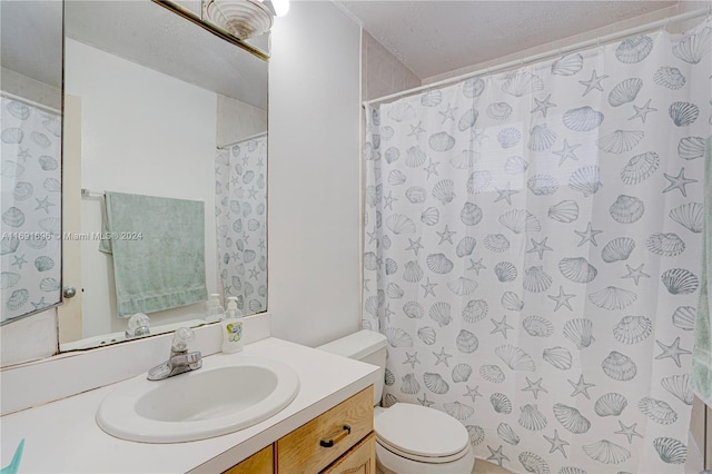 bathroom featuring toilet, vanity, a textured ceiling, and walk in shower