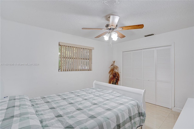 tiled bedroom featuring a textured ceiling, ceiling fan, and a closet