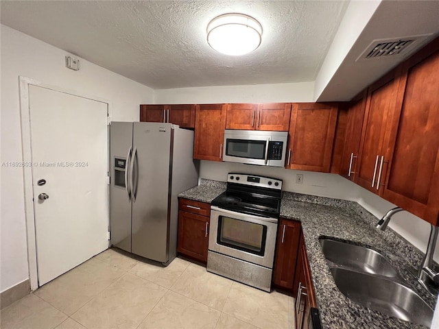 kitchen with dark stone countertops, a textured ceiling, sink, and appliances with stainless steel finishes