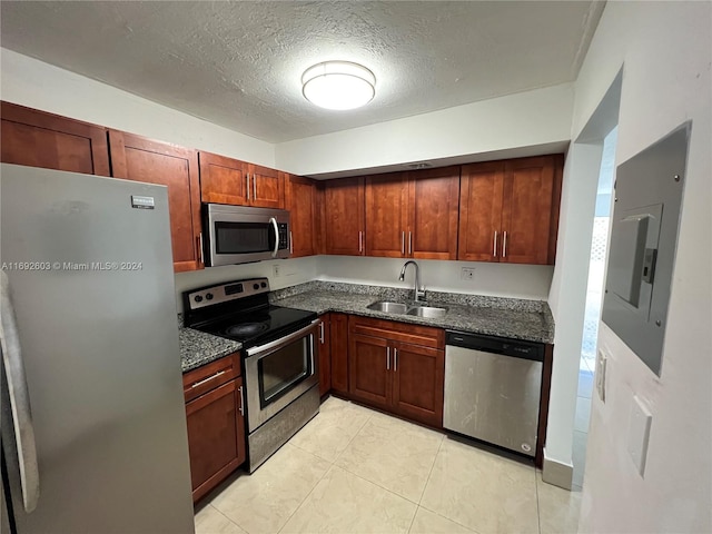 kitchen featuring stainless steel appliances, sink, dark stone countertops, a textured ceiling, and electric panel