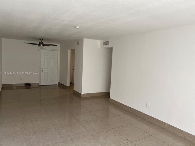 tiled empty room featuring a textured ceiling and ceiling fan