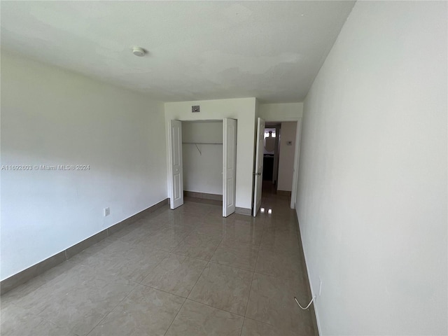 unfurnished bedroom featuring tile patterned flooring and a closet