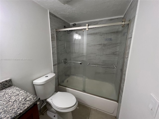 full bathroom featuring bath / shower combo with glass door, tile patterned flooring, a textured ceiling, and toilet