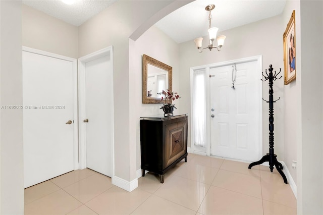 entryway with a chandelier, a textured ceiling, and light tile patterned floors