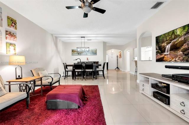 living room featuring ceiling fan with notable chandelier, a textured ceiling, and light tile patterned flooring