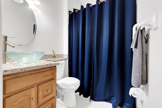 bathroom with toilet, vanity, and tile patterned flooring