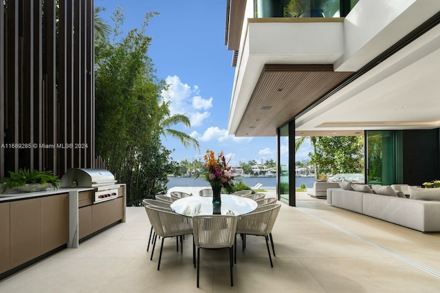 view of patio with outdoor lounge area, a grill, a water view, and exterior kitchen