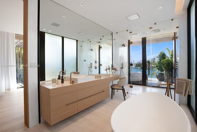 bathroom with a water view, separate shower and tub, hardwood / wood-style flooring, vanity, and a wall of windows