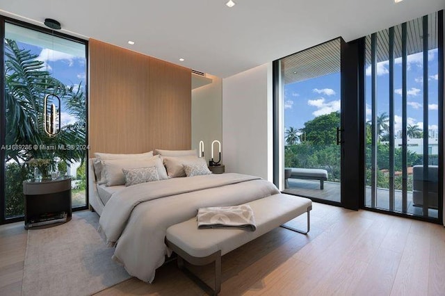 bedroom with access to exterior, a wall of windows, and light wood-type flooring