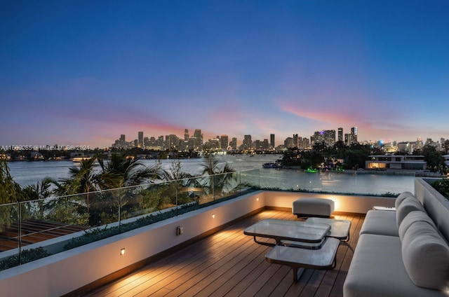 deck at dusk with an outdoor living space and a water view