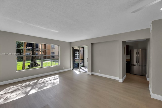 unfurnished living room with a textured ceiling and light hardwood / wood-style floors