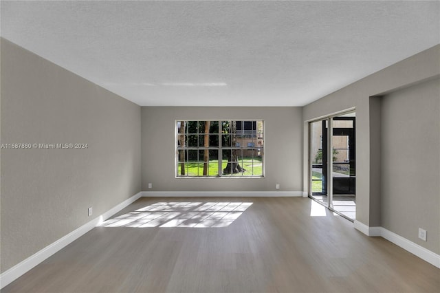 spare room with light wood-type flooring and a textured ceiling