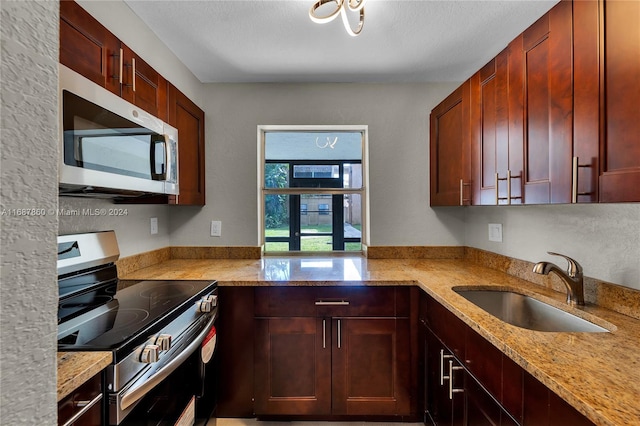 kitchen featuring light stone countertops, a textured ceiling, sink, and appliances with stainless steel finishes