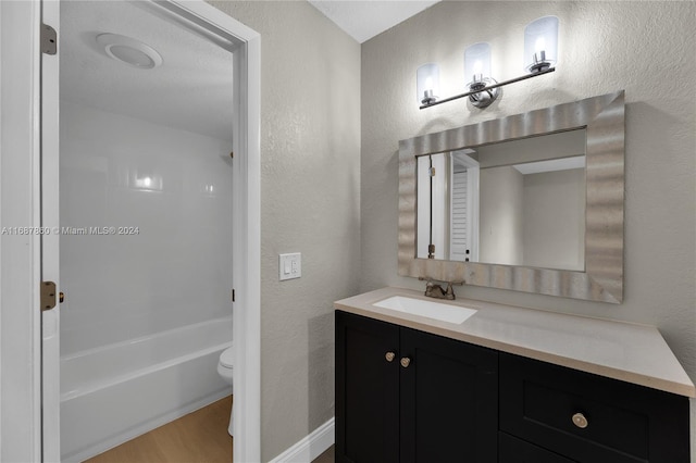 full bathroom featuring hardwood / wood-style floors, tub / shower combination, vanity, and toilet