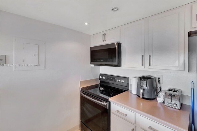 kitchen featuring white cabinetry and electric range