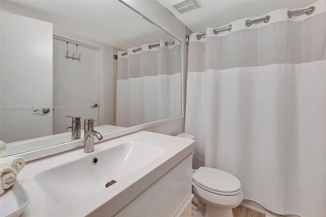 bathroom with curtained shower, vanity, and toilet