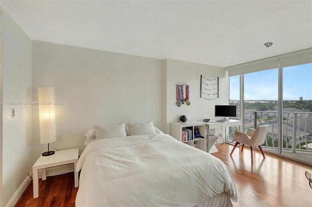 bedroom featuring hardwood / wood-style floors, access to outside, and expansive windows