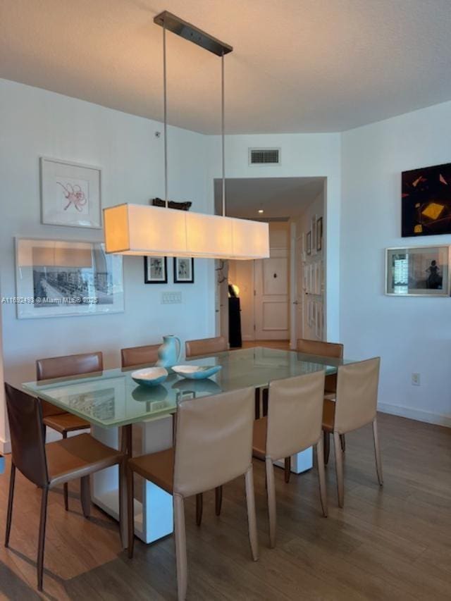 dining space with wood finished floors, visible vents, and baseboards