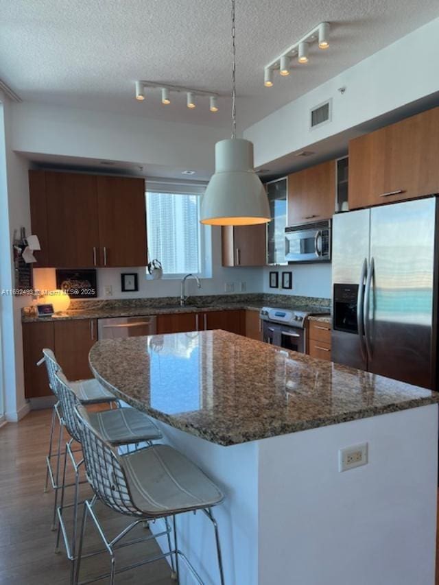 kitchen featuring a breakfast bar, a sink, visible vents, appliances with stainless steel finishes, and light wood finished floors