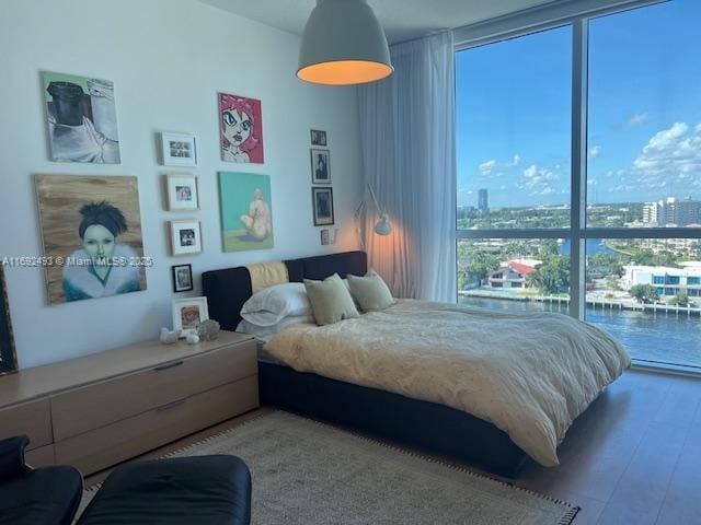 bedroom featuring a wall of windows, a view of city, and wood finished floors