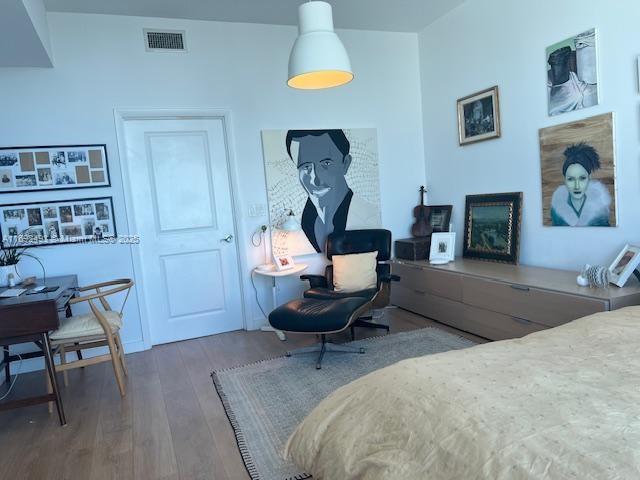 bedroom featuring visible vents, a fireplace with raised hearth, and wood finished floors