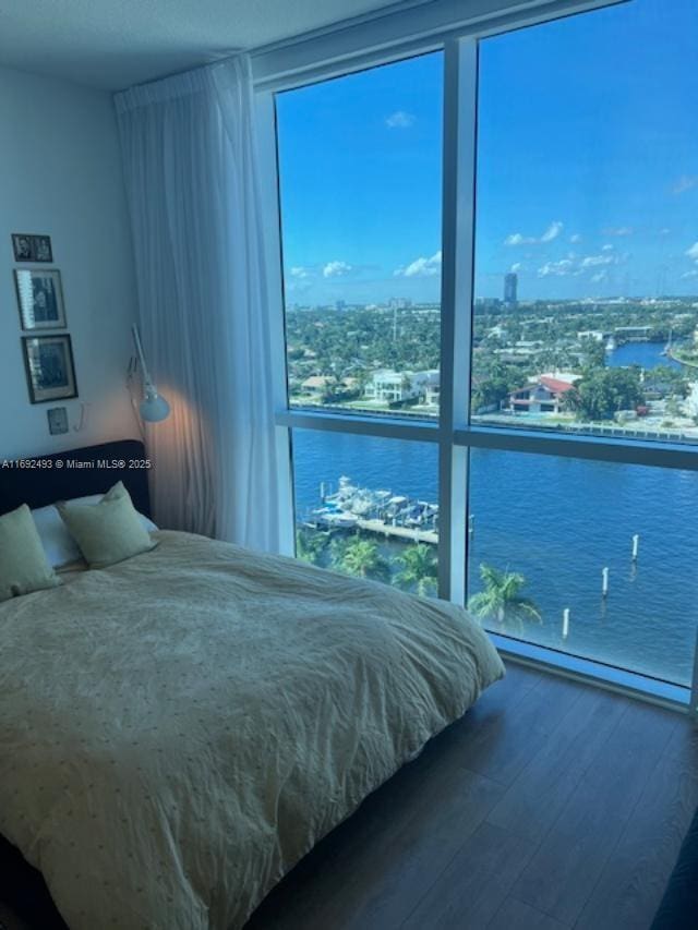 bedroom with a view of city, baseboard heating, a water view, and wood finished floors