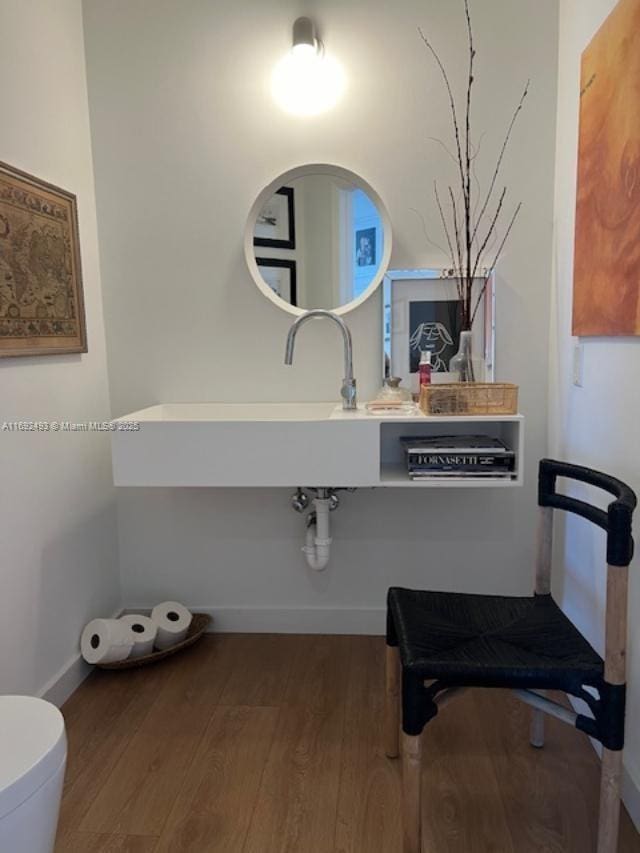 bathroom with baseboards, toilet, and wood finished floors