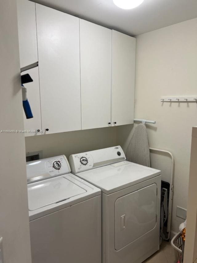 laundry room featuring cabinet space, light tile patterned floors, and separate washer and dryer