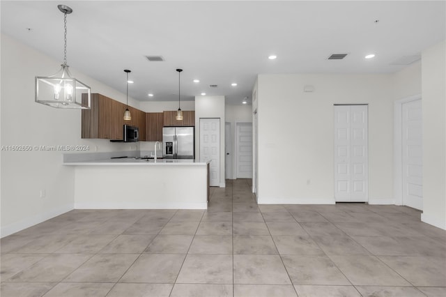 kitchen with stainless steel appliances, kitchen peninsula, decorative light fixtures, sink, and a chandelier