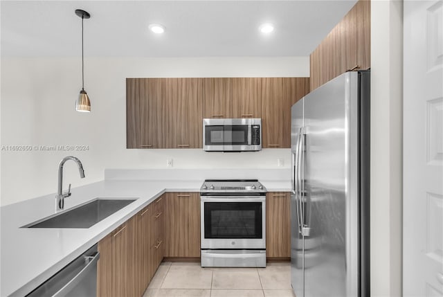 kitchen featuring light tile patterned floors, sink, decorative light fixtures, and appliances with stainless steel finishes