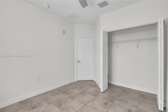 unfurnished bedroom with light tile patterned floors, ceiling fan, and a closet