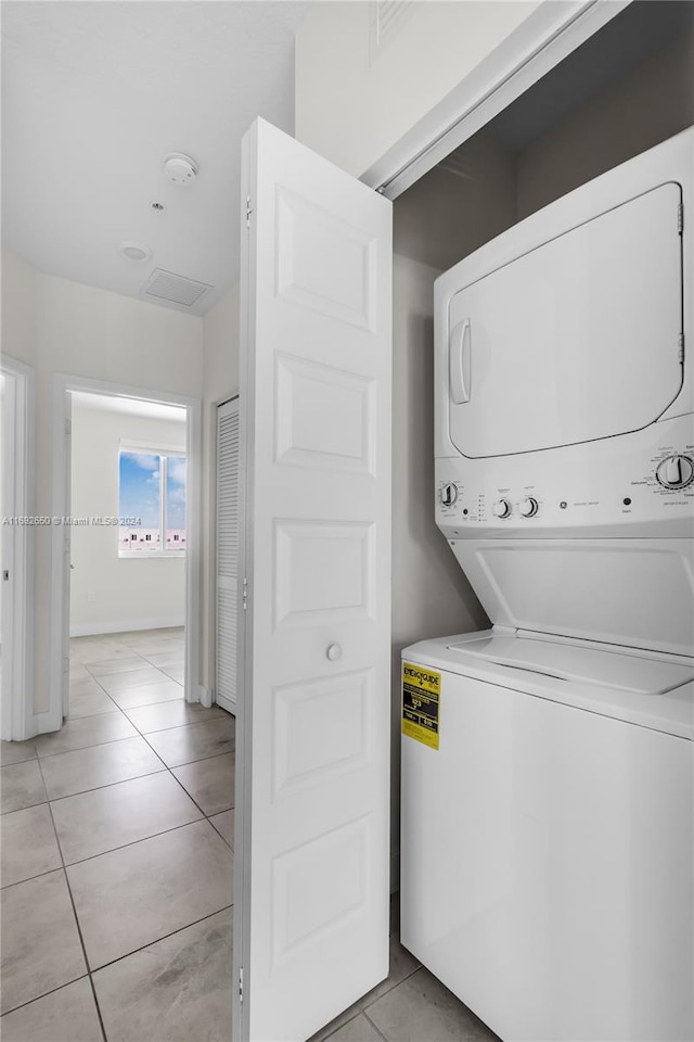 laundry area featuring stacked washing maching and dryer and light tile patterned flooring