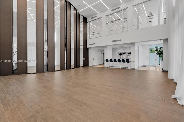 unfurnished living room featuring a high ceiling and hardwood / wood-style flooring