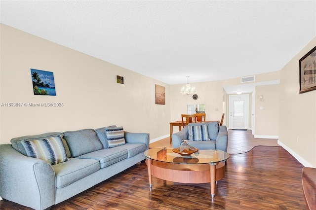 living room featuring dark hardwood / wood-style flooring, a chandelier, and a textured ceiling