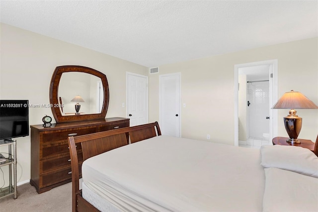 bedroom featuring light colored carpet, connected bathroom, and a textured ceiling