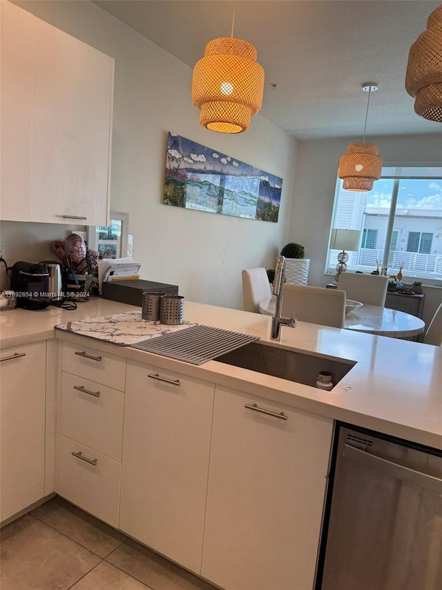 kitchen featuring white cabinets, hanging light fixtures, light tile patterned flooring, and dishwasher