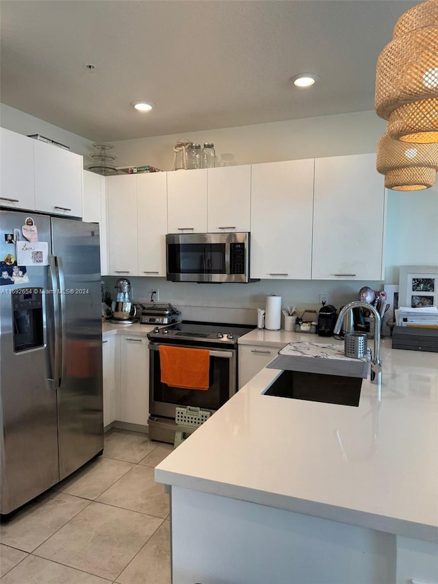 kitchen with stainless steel appliances, white cabinetry, sink, kitchen peninsula, and light tile patterned floors