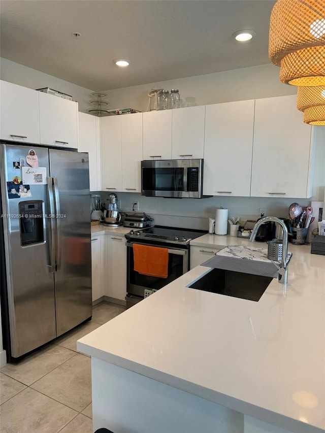 kitchen featuring kitchen peninsula, sink, light tile patterned flooring, white cabinetry, and appliances with stainless steel finishes