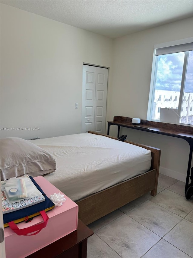 tiled bedroom featuring a textured ceiling and a closet