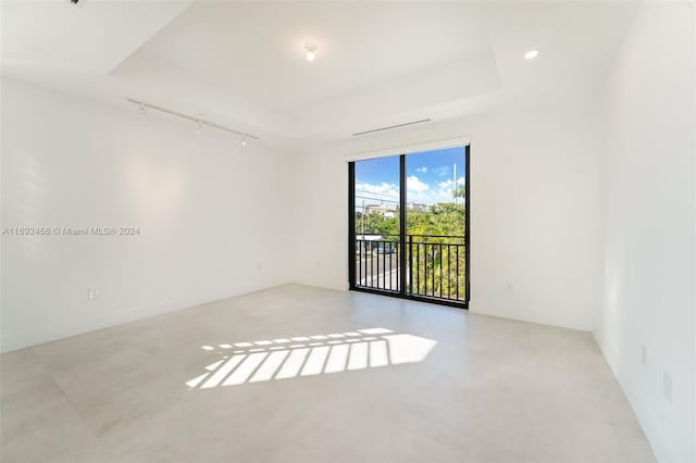 unfurnished room featuring rail lighting and a raised ceiling