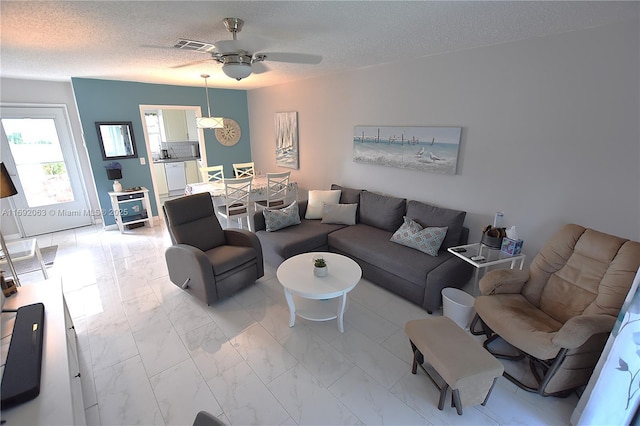 living room with ceiling fan and a textured ceiling