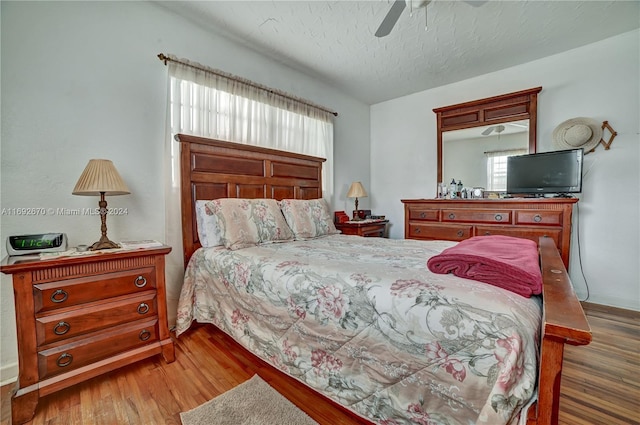 bedroom featuring ceiling fan, a textured ceiling, and dark hardwood / wood-style floors