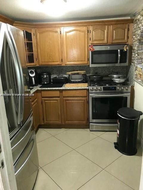 kitchen with backsplash, appliances with stainless steel finishes, and light tile patterned flooring